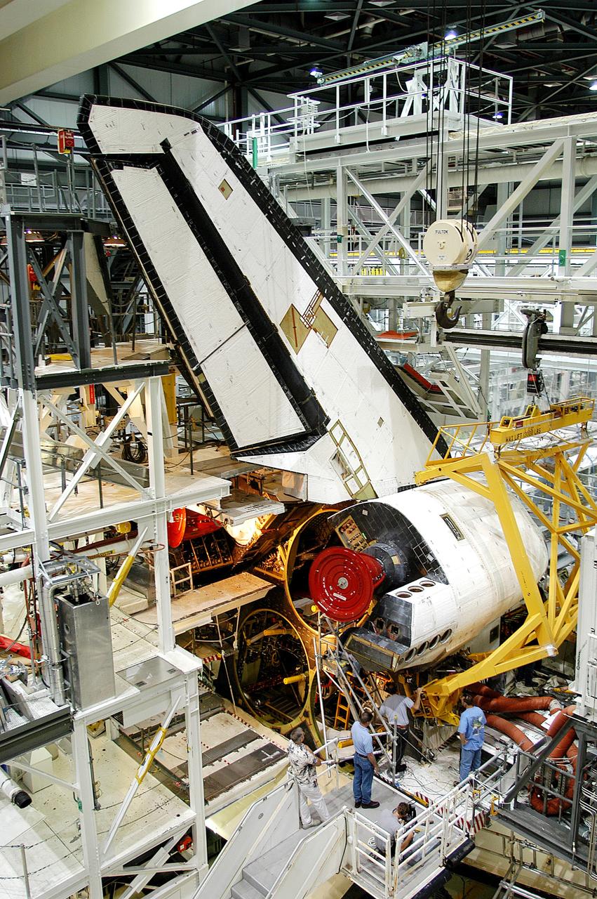KENNEDY SPACE CENTER, FLA. - Workers in the Orbiter Processing Facility prepare to remove one of two orbital maneuvering system (OMS) pods from Endeavour. The OMS pods are attached to the upper aft fuselage left and right sides. Fabricated primarily of graphite epoxy composite and aluminum, each pod is 21.8 feet long and 11.37 feet wide at its aft end and 8.41 feet wide at its forward end, with a surface area of approximately 435 square feet. Each pod houses the Reaction Control System propulsion components used for inflight maneuvering and is attached to the aft fuselage with 11 bolts. OMS pods are removed during Orbiter Major Modifications. Once removed, the OMS pods undergo in-depth structural inspections, system checks and the thrusters are changed out.