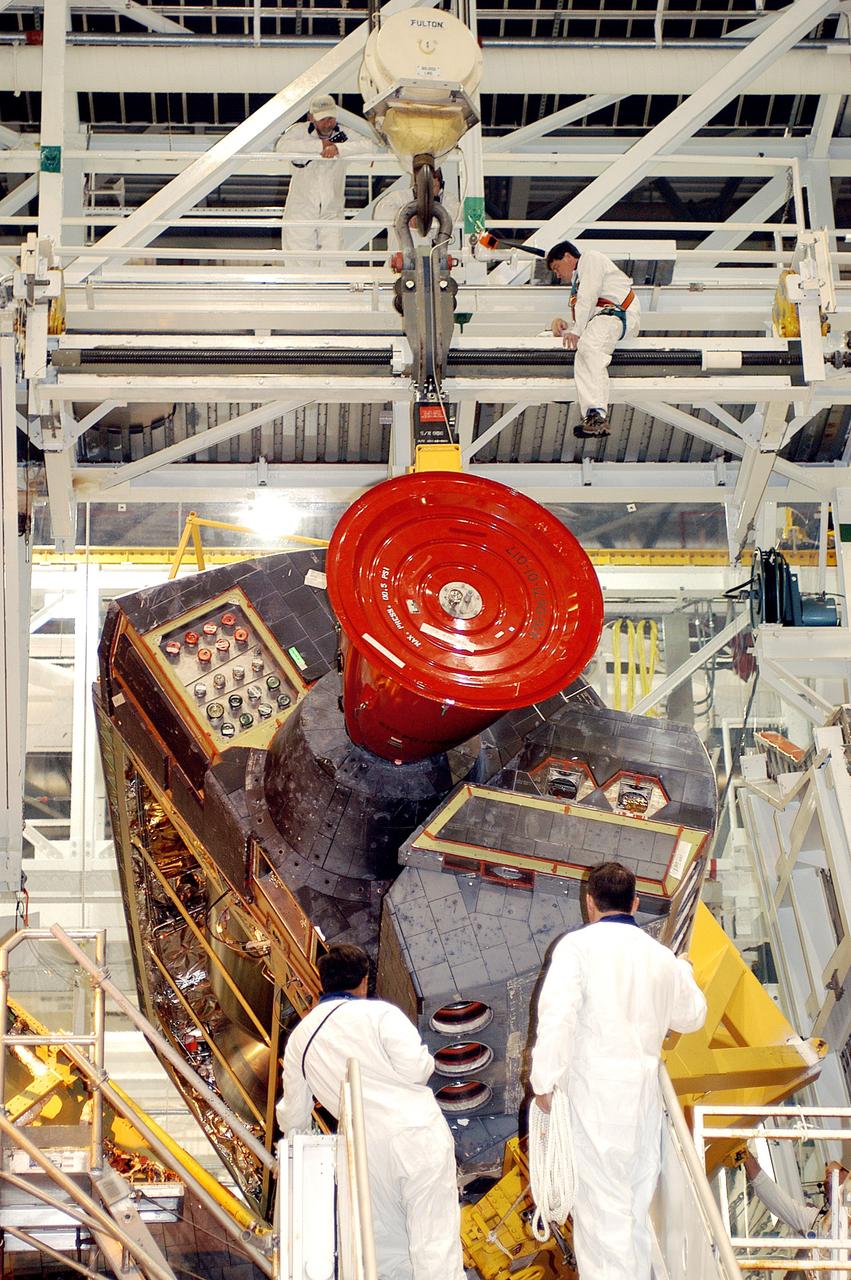 KENNEDY SPACE CENTER, FLA. - Technicians in the Orbiter Processing Facility oversee removal of one of two orbital maneuvering system (OMS) pods from Endeavour. The OMS pods are attached to the upper aft fuselage left and right sides. Fabricated primarily of graphite epoxy composite and aluminum, each pod is 21.8 feet long and 11.37 feet wide at its aft end and 8.41 feet wide at its forward end, with a surface area of approximately 435 square feet. Each pod houses the Reaction Control System propulsion components used for inflight maneuvering and is attached to the aft fuselage with 11 bolts. OMS pods are removed during Orbiter Major Modifications. Once removed, the OMS pods undergo in-depth structural inspections, system checks and the thrusters are changed out.