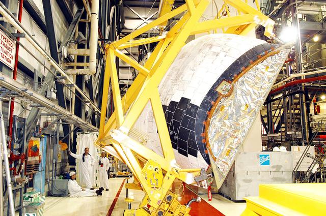 NASA image: KENNEDY SPACE CENTER, FLA. -  In the Orbiter Processing Facility, one of two orbital maneuvering system (OMS) pods removed from Endeavour is lowered onto a transporter.  The OMS pods are attached to the upper aft fuselage left and right sides.  Fabricated primarily of graphite epoxy composite and aluminum, each pod is 21.8 feet long and 11.37 feet wide at its aft end and 8.41 feet wide at its forward end, with a surface area of approximately 435 square feet.  Each pod houses the Reaction Control System propulsion components used for inflight maneuvering and is attached to the aft fuselage with 11 bolts.   OMS pods are removed during Orbiter Major Modifications. Once removed, the OMS pods undergo in-depth structural inspections, system checks and the thrusters are changed out.