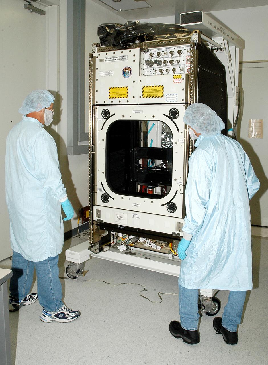 KENNEDY SPACE CENTER, FLA. -  Workers in the Space Station Processing Facility check out the Window Observational Research Facility (WORF),  designed and built by the Boeing Co. at NASA’s Marshall Space Flight Center in Huntsville, Ala.   WORF will be delivered to the International Space Station and placed in the rack position in front of the Destiny lab window,  providing locations for attaching cameras, multi-spectral scanners and other instruments. WORF will support a variety of scientific and commercial experiments in areas of Earth systems and processes, global ecological changes in Earth’s biosphere, lithosphere, hydrosphere and climate system, Earth resources, natural hazards, and education.  After installation, it will become a permanent focal point for Earth Science research aboard the space station.