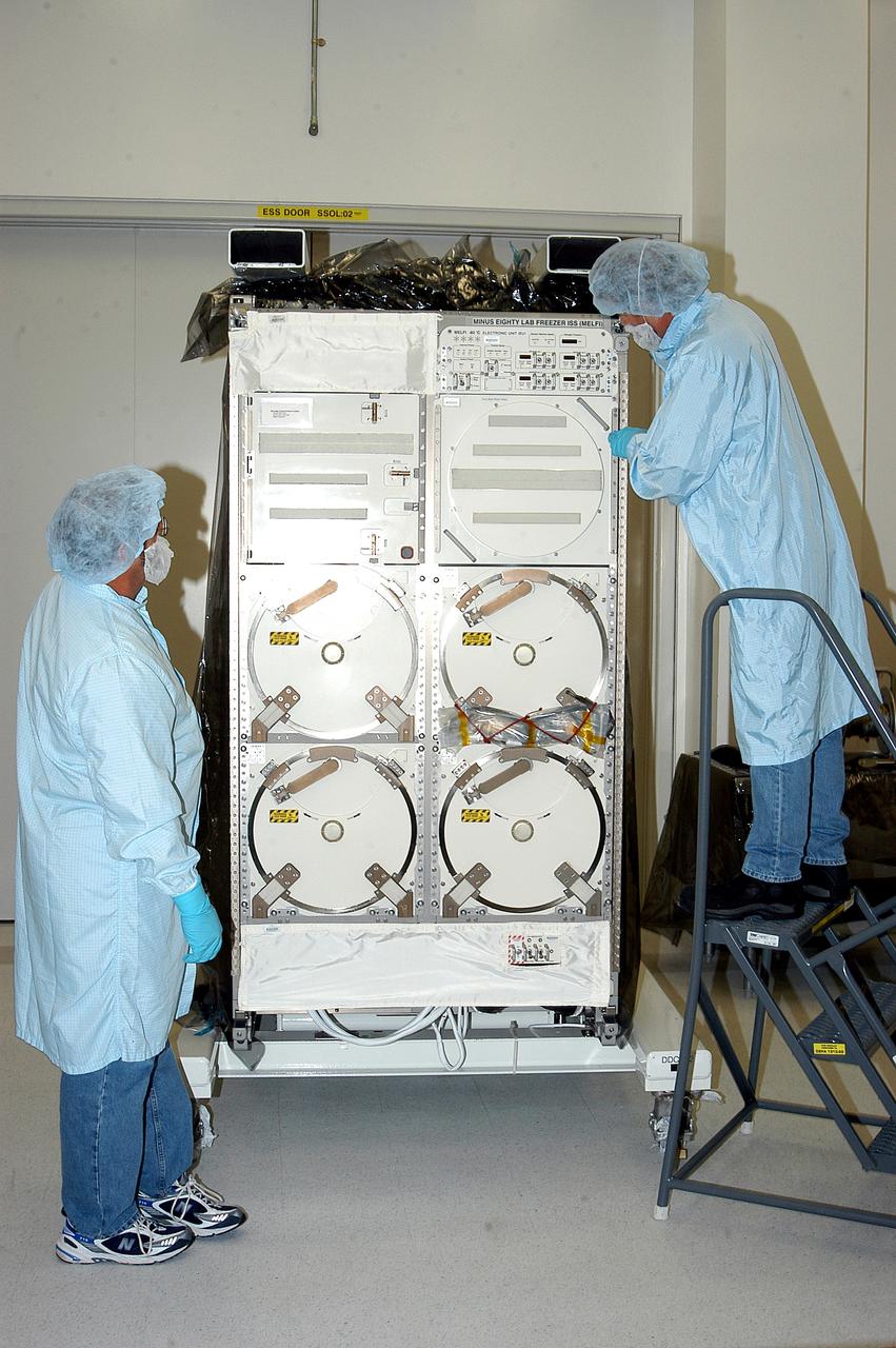 KENNEDY SPACE CENTER, FLA. -  After removing its cover, technicians look over the Minus Eighty Lab Freezer for ISS (MELFI),  provided as Laboratory Support Equipment by the European Space Agency for the International Space Station.  The lab will provide cooling and storage for reagents, samples and perishable materials in four insulated containers called dewars with independently selectable temperatures of -80°C, -26°C, and +4°C. It also will be used to transport samples to and from the station.   The MELFI is planned for launch on the ULF-1 mission.