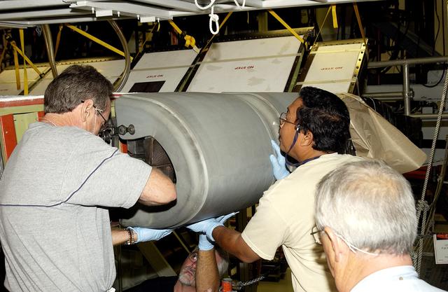 NASA image: KENNEDY SPACE CENTER, FLA. -  In the Orbiter Processing Facility, United Space Alliance workers Mike Hyatt (left), Saul Ngy (center) and Jerry Belt (right) prepare to install a Reinforced Carbon Carbon (RCC) panel to the leading edge of the wing of the orbiter Atlantis.  The gray carbon composite RCC panels have sufficient strength to withstand the aerodynamic forces experienced during launch and reentry, which can reach as high as 800 pounds per square foot.  The operating range of RCC is from minus 250º F to about 3,000º F, the temperature produced by friction with the atmosphere during reentry.