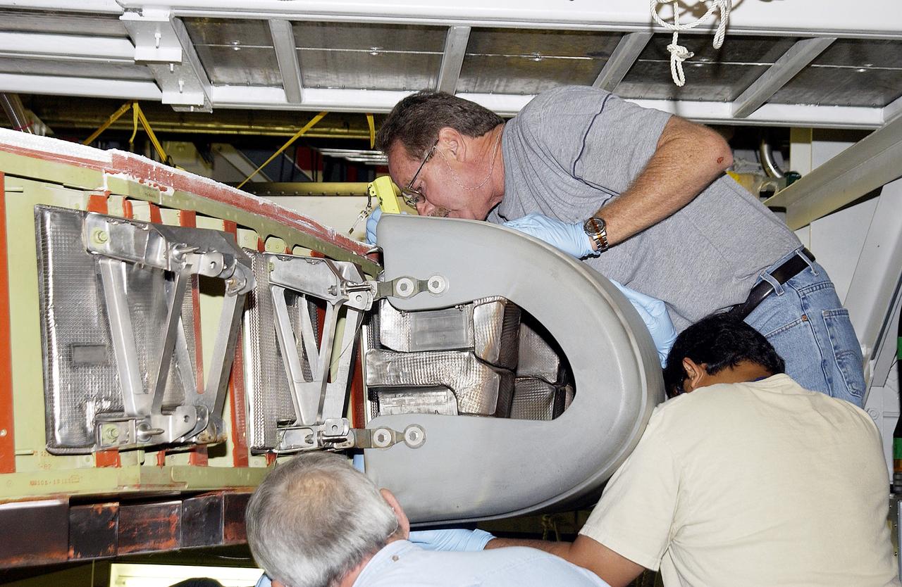 KENNEDY SPACE CENTER, FLA. -  In the Orbiter Processing Facility, United Space Alliance workers  Mike Hyatt (above),  Saul Ngy (right) and Jerry Belt (below) install a Reinforced Carbon Carbon (RCC) panel to the leading edge of the wing of the orbiter Atlantis.  The gray carbon composite RCC panels have sufficient strength to withstand the aerodynamic forces experienced during launch and reentry, which can reach as high as 800 pounds per square foot.  The operating range of RCC is from minus 250º F to about 3,000º F, the temperature produced by friction with the atmosphere during reentry.