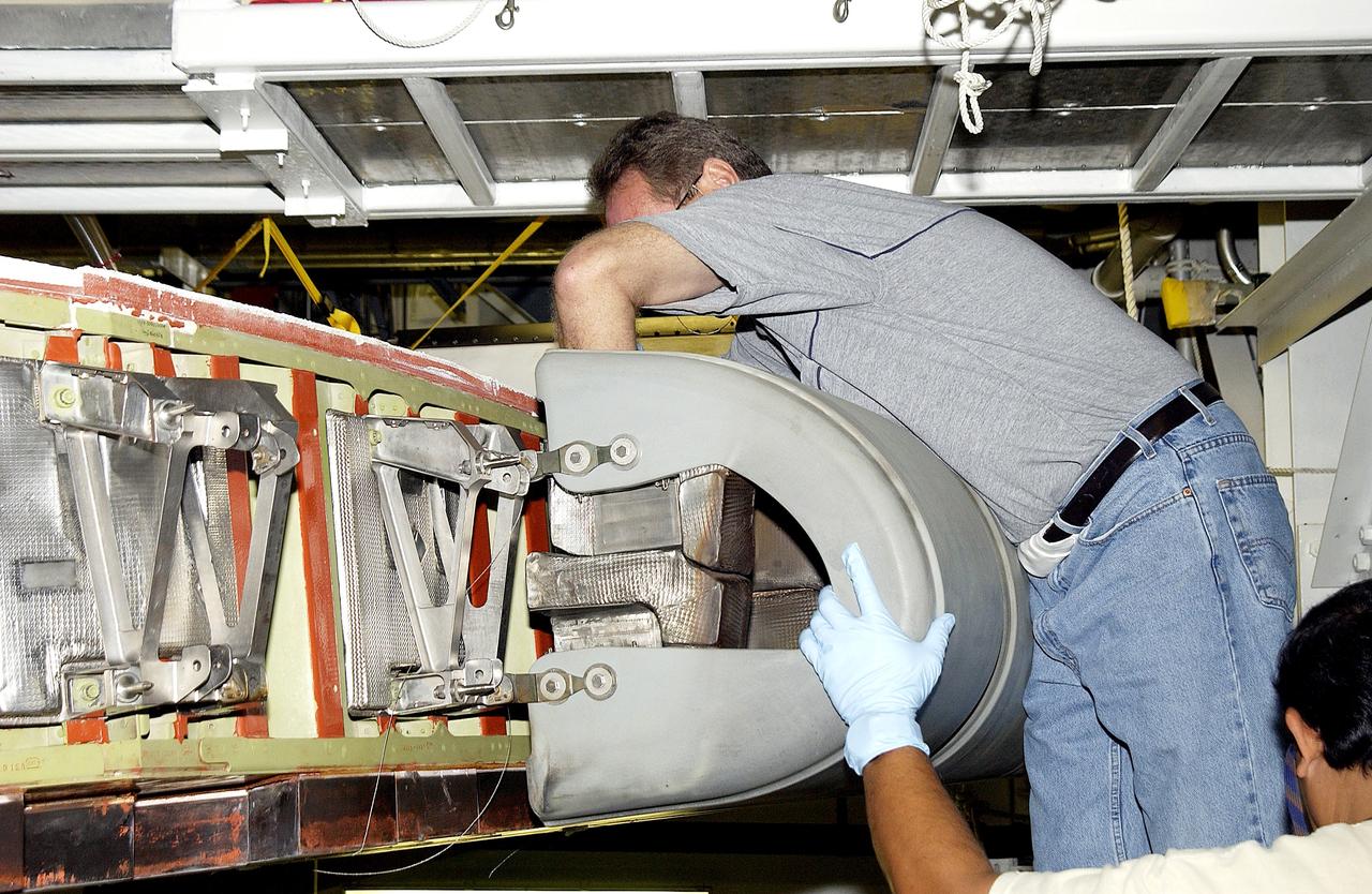 KENNEDY SPACE CENTER, FLA. - In the Orbiter Processing Facility, United Space Alliance workers Mike Hyatt (above) and Saul Ngy (below right) finish installing a Reinforced Carbon Carbon (RCC) panel to the leading edge of the wing of the orbiter Atlantis.  The gray carbon composite RCC panels have sufficient strength to withstand the aerodynamic forces experienced during launch and reentry, which can reach as high as 800 pounds per square foot.  The operating range of RCC is from minus 250º F to about 3,000º F, the temperature produced by friction with the atmosphere during reentry.