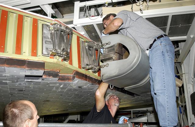 NASA image: KENNEDY SPACE CENTER, FLA. - In the Orbiter Processing Facility, United Space Alliance worker Mike Hyatt (above) finishes installing a Reinforced Carbon Carbon (RCC) panel to the leading edge of the wing of the orbiter Atlantis.  The gray carbon composite RCC panels have sufficient strength to withstand the aerodynamic forces experienced during launch and reentry, which can reach as high as 800 pounds per square foot.  The operating range of RCC is from minus 250º F to about 3,000º F, the temperature produced by friction with the atmosphere during reentry.