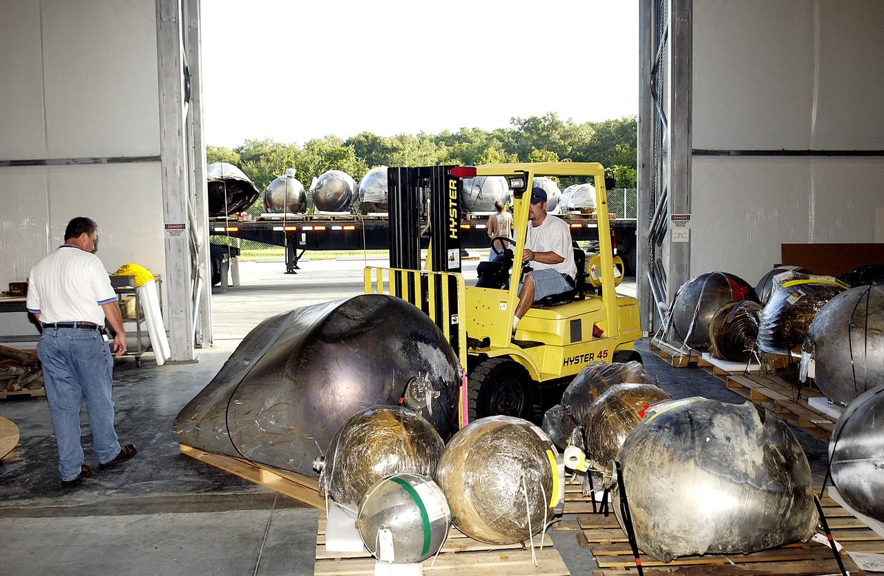 KENNEDY SPACE CENTER, FLA. -    Some of the Columbia debris inside the Columbia Debris Hangar is being moved out and placed on a flatbed truck (seen in the background) for transfer to the Vehicle Assembly Building for permanent storage.  More than 83,000  pieces of debris were shipped to KSC during search and recovery efforts in East Texas. That represents about 38 percent of the dry weight of Columbia, equaling almost 85,000 pounds.