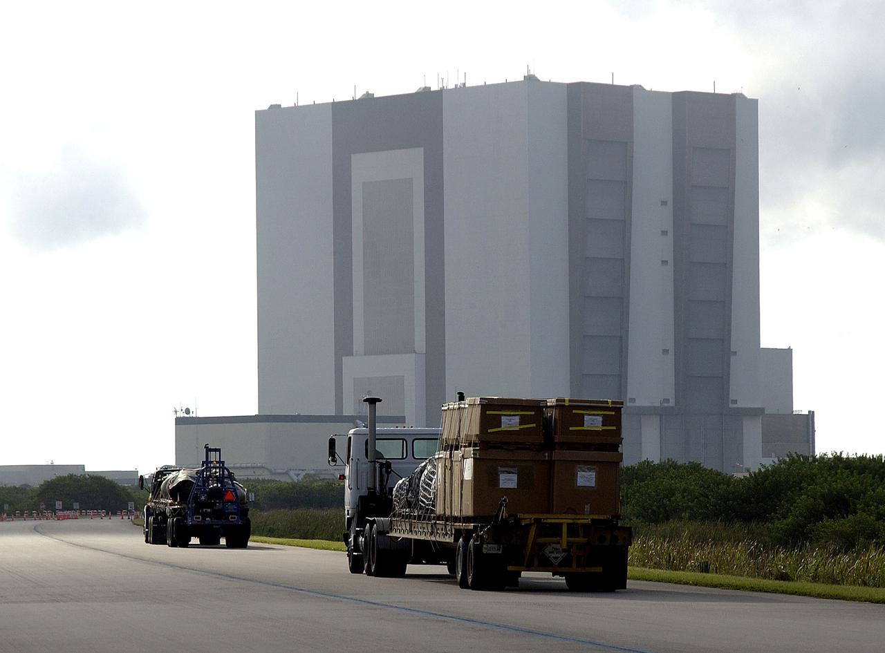 KENNEDY SPACE CENTER, FLA. -  Flatbed trucks carrying some of the debris of Space Shuttle Columbia approach the Vehicle Assembly Building (VAB).  The debris is being transferred from the Columbia Debris Hangar to the VAB for permanent storage.  More than 83,000 pieces of debris were shipped to KSC during search and recovery efforts in East Texas. That represents about 38 percent of the dry weight of Columbia, equaling almost 85,000 pounds.