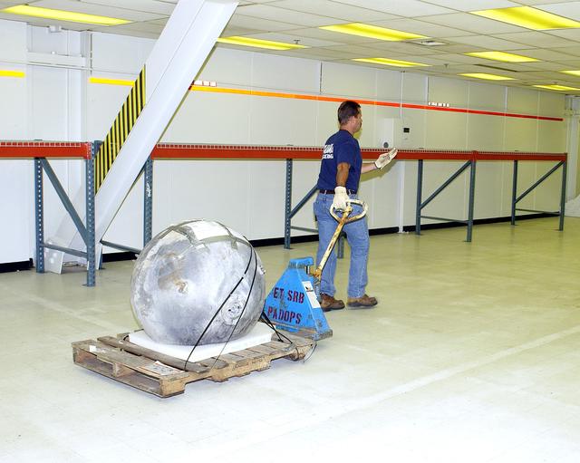 NASA image: KENNEDY SPACE CENTER, FLA. -  A worker moves some of the Columbia debris to its storage site in the Vehicle Assembly Building (VAB). The debris is being transferred from the Columbia Debris Hangar to the VAB for permanent storage.  More than 83,000 pieces of debris were shipped to KSC during search and recovery efforts in East Texas. That represents about 38 percent of the dry weight of Columbia, equaling almost 85,000 pounds.