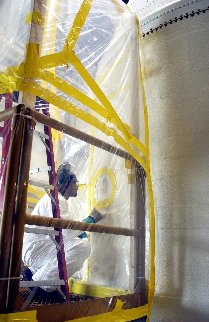 KENNEDY SPACE CENTER, FLA. -  In the Solid Rocket Booster Assembly and Refurbishment Facility (ARF), Vernon Gibbs, with United Space Alliance, prepares the forward skirt of a solid rocket booster for installation of the parachute camera.  Refurbishment and subassembly of Shuttle SRB hardware - primarily the forward and aft assemblies - is carried out in the ARF.