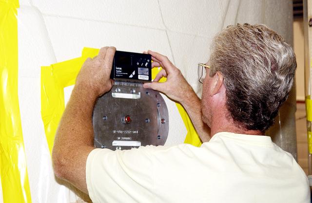 NASA image: KENNEDY SPACE CENTER, FLA. -  Mark Northcraft adjusts the position of the parachute camera just installed on the solid rocket booster forward skirt in the Solid Rocket Booster Assembly and Refurbishment Facility (ARF).  Refurbishment and subassembly of Shuttle SRB hardware - primarily the forward and aft assemblies - is carried out in the ARF.