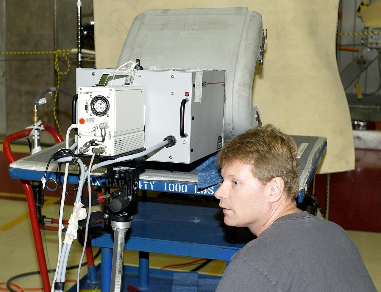 KENNEDY SPACE CENTER, FLA. - In the Orbiter Processing Facility,  Jim Landy, NDE specialist with United Space Alliance (USA), watches a monitor off-screen to examine a Reinforced Carbon Carbon panel using flash thermography.  Attached to the leading edge of the wing of the orbiters,  the gray carbon composite RCC panels have sufficient strength to withstand the aerodynamic forces experienced during launch and reentry, which can reach as high as 800 pounds per square foot.  The operating range of RCC is from minus 250º F to about 3,000º F, the temperature produced by friction with the atmosphere during reentry.