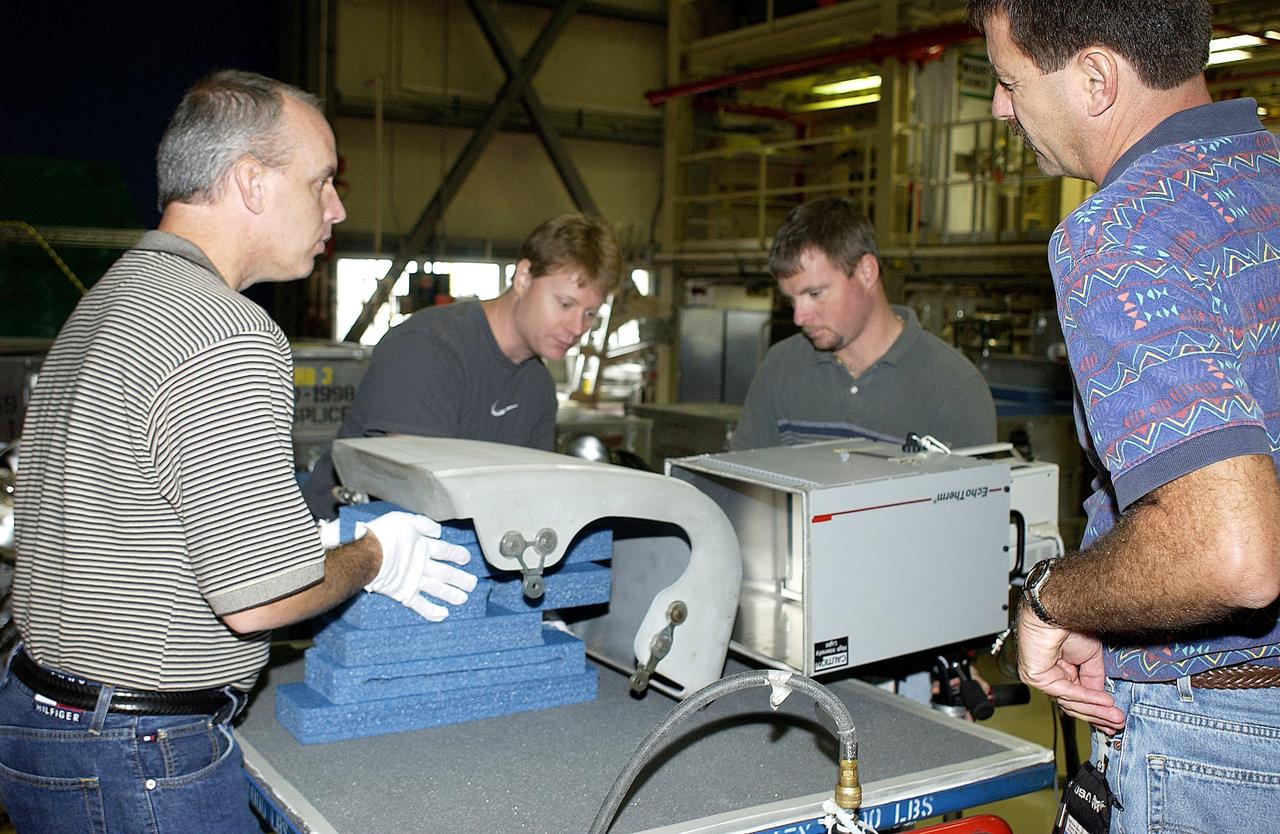 KENNEDY SPACE CENTER, FLA. - In the Orbiter Processing Facility, United Space Alliance workers share the task of examining  a Reinforced Carbon Carbon panel using flash thermography.  From left are Dan Kenna, Jim Landy, Paul Ogletree and Dan Phillips.  Attached to the leading edge of the wing of the orbiters,  the gray carbon composite RCC panels have sufficient strength to withstand the aerodynamic forces experienced during launch and reentry, which can reach as high as 800 pounds per square foot.  The operating range of RCC is from minus 250º F to about 3,000º F, the temperature produced by friction with the atmosphere during reentry.