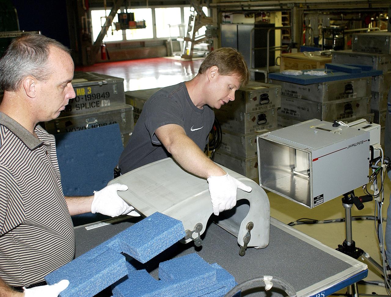 KENNEDY SPACE CENTER, FLA. - In the Orbiter Processing Facility, United Space Alliance workers Dan Kenna and Jim Landy prepare to examine a Reinforced Carbon Carbon panel using flash thermography.  Attached to the leading edge of the wing of the orbiters,  the gray carbon composite RCC panels have sufficient strength to withstand the aerodynamic forces experienced during launch and reentry, which can reach as high as 800 pounds per square foot.  The operating range of RCC is from minus 250º F to about 3,000º F, the temperature produced by friction with the atmosphere during reentry.
