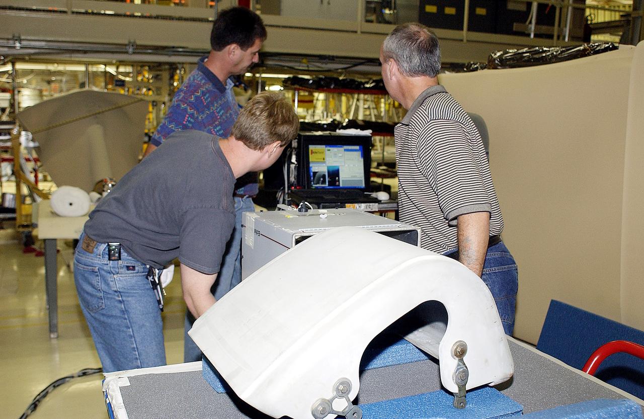 KENNEDY SPACE CENTER, FLA. - In the Orbiter Processing Facility, United Space Alliance workers Jim Landy (front), Dan Phillips and Dan Kenna watch a monitor showing results of flash thermography on the Reinforced Carbon Carbon panel on the table (foreground).  Attached to the leading edge of the wing of the orbiters,  the gray carbon composite RCC panels have sufficient strength to withstand the aerodynamic forces experienced during launch and reentry, which can reach as high as 800 pounds per square foot.  The operating range of RCC is from minus 250º F to about 3,000º F, the temperature produced by friction with the atmosphere during reentry.