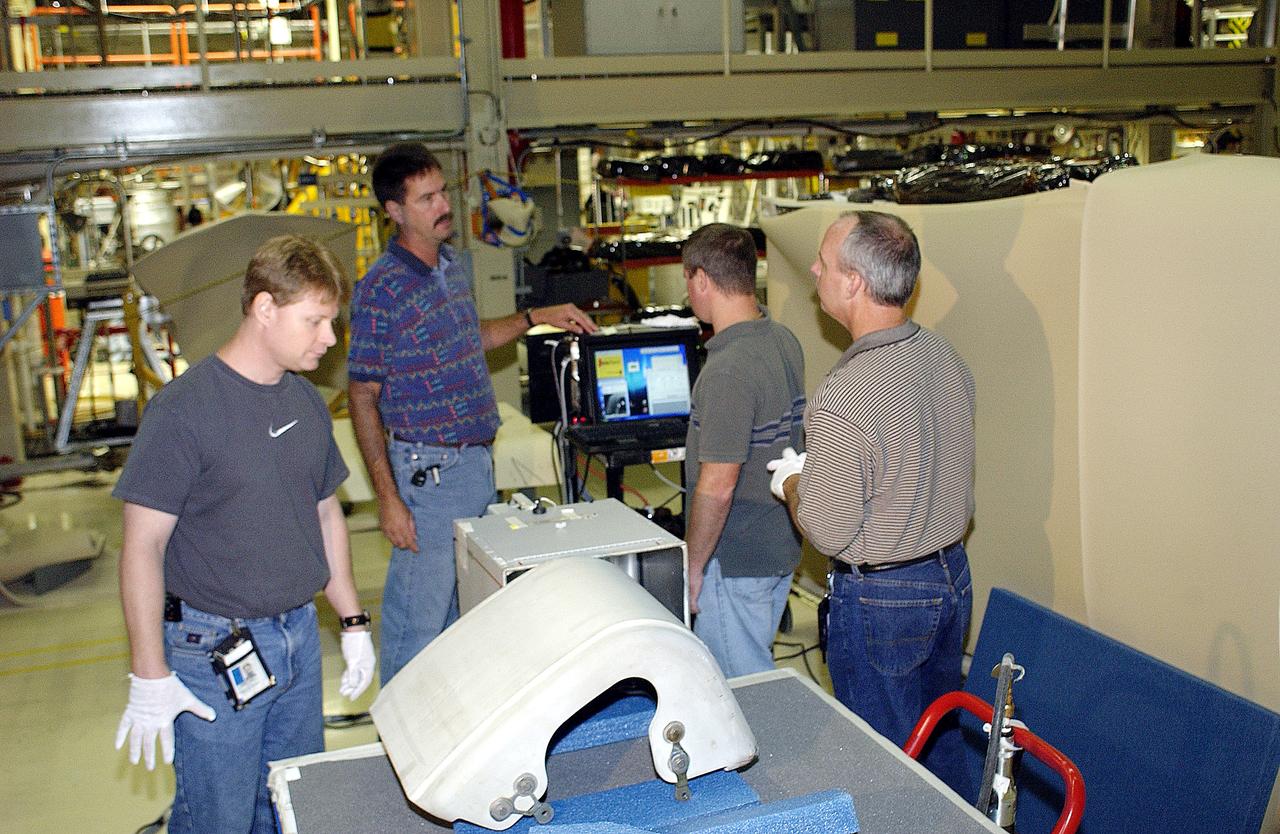 KENNEDY SPACE CENTER, FLA. - In the Orbiter Processing Facility, United Space Alliance workers (left to right) Jim Landy, Dan Phillips, Paul Ogletree and Dan Kenna check results of flash thermography on the Reinforced Carbon Carbon panel on the table (foreground).  Attached to the leading edge of the wing of the orbiters,  the gray carbon composite RCC panels have sufficient strength to withstand the aerodynamic forces experienced during launch and reentry, which can reach as high as 800 pounds per square foot.  The operating range of RCC is from minus 250º F to about 3,000º F, the temperature produced by friction with the atmosphere during reentry.