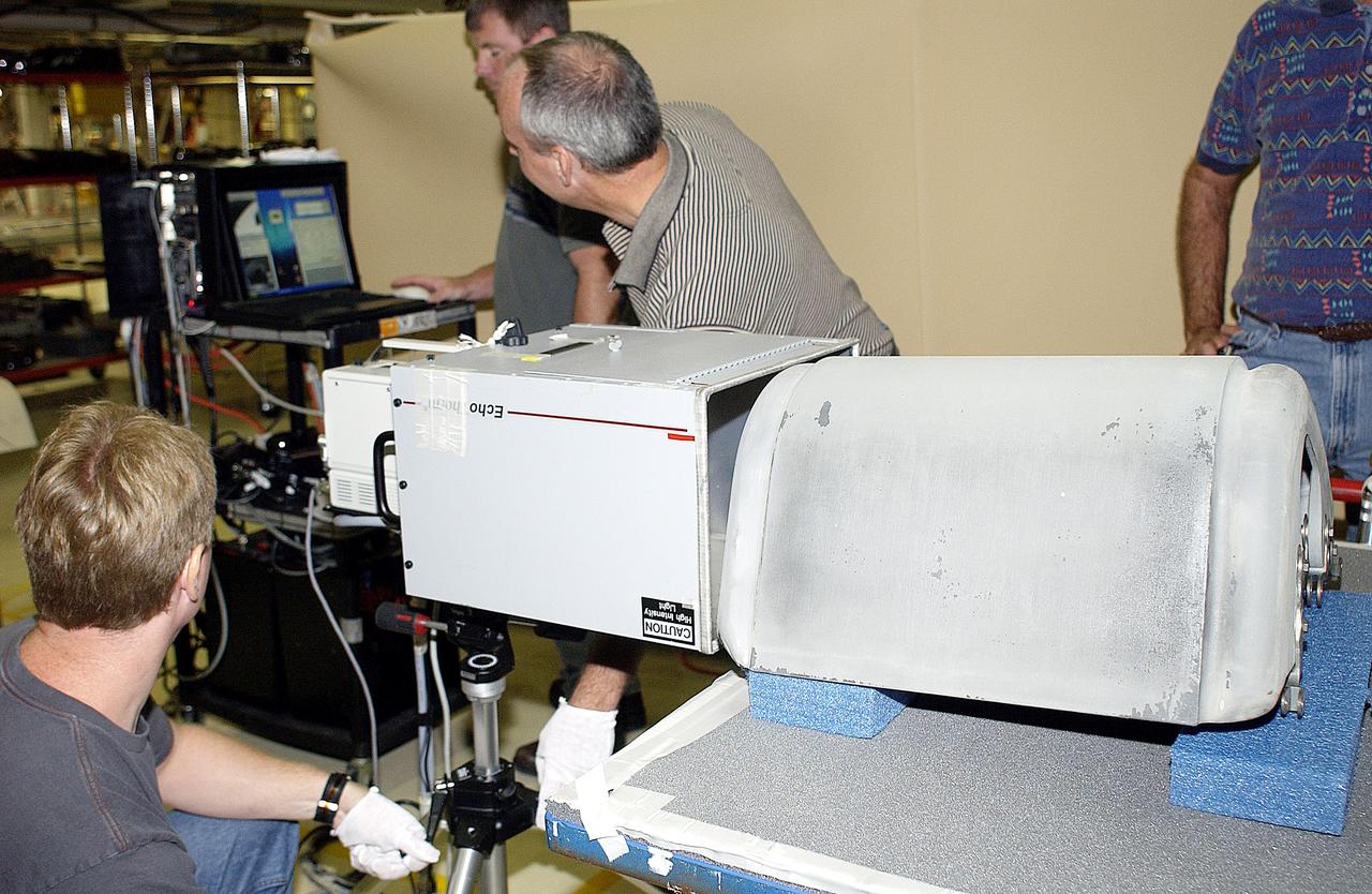 KENNEDY SPACE CENTER, FLA. - In the Orbiter Processing Facility, United Space Alliance workers (left to right) Jim Landy, Paul Ogletree, Dan Kenna and Dan Phillips check results of flash thermography on the Reinforced Carbon Carbon panel on the table (foreground).  Attached to the leading edge of the wing of the orbiters,  the gray carbon composite RCC panels have sufficient strength to withstand the aerodynamic forces experienced during launch and reentry, which can reach as high as 800 pounds per square foot.  The operating range of RCC is from minus 250º F to about 3,000º F, the temperature produced by friction with the atmosphere during reentry.