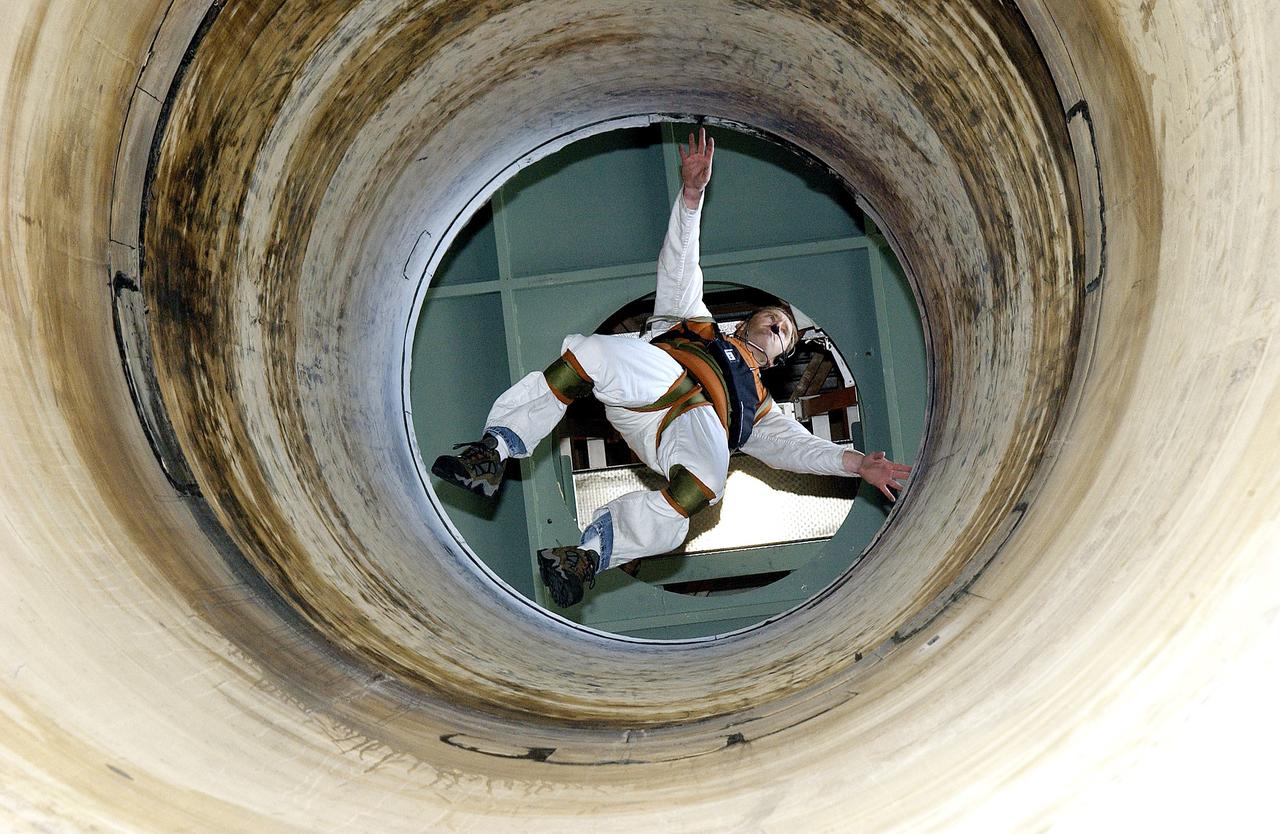 KENNEDY SPACE CENTER, FLA. -   Seen from below and through a solid rocket booster segment mockup, Jeff Thon, an SRB mechanic with United Space Alliance, tests the feasibility of a vertical solid rocket booster propellant grain inspection technique.  The inspection of segments is required as part of safety analysis.