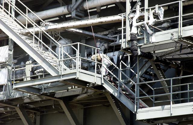 NASA image: KENNEDY SPACE CENTER, FLA. - Workers, covered in protective clothing and breathing apparatus, continue sandblasting on the Mobile Launcher Platform on Launch Pad 39A to remove corrosion before repainting.  Routine maintenance includes sandblasting and repainting as preventive means to minimize corrosion.