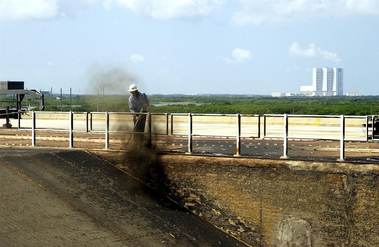 KENNEDY SPACE CENTER, FLA. - A worker sandblasts the surface behind the Mobile Launcher Platform on Launch Pad 39A .  Routine maintenance includes sandblasting and repainting as preventive means to minimize corrosion.