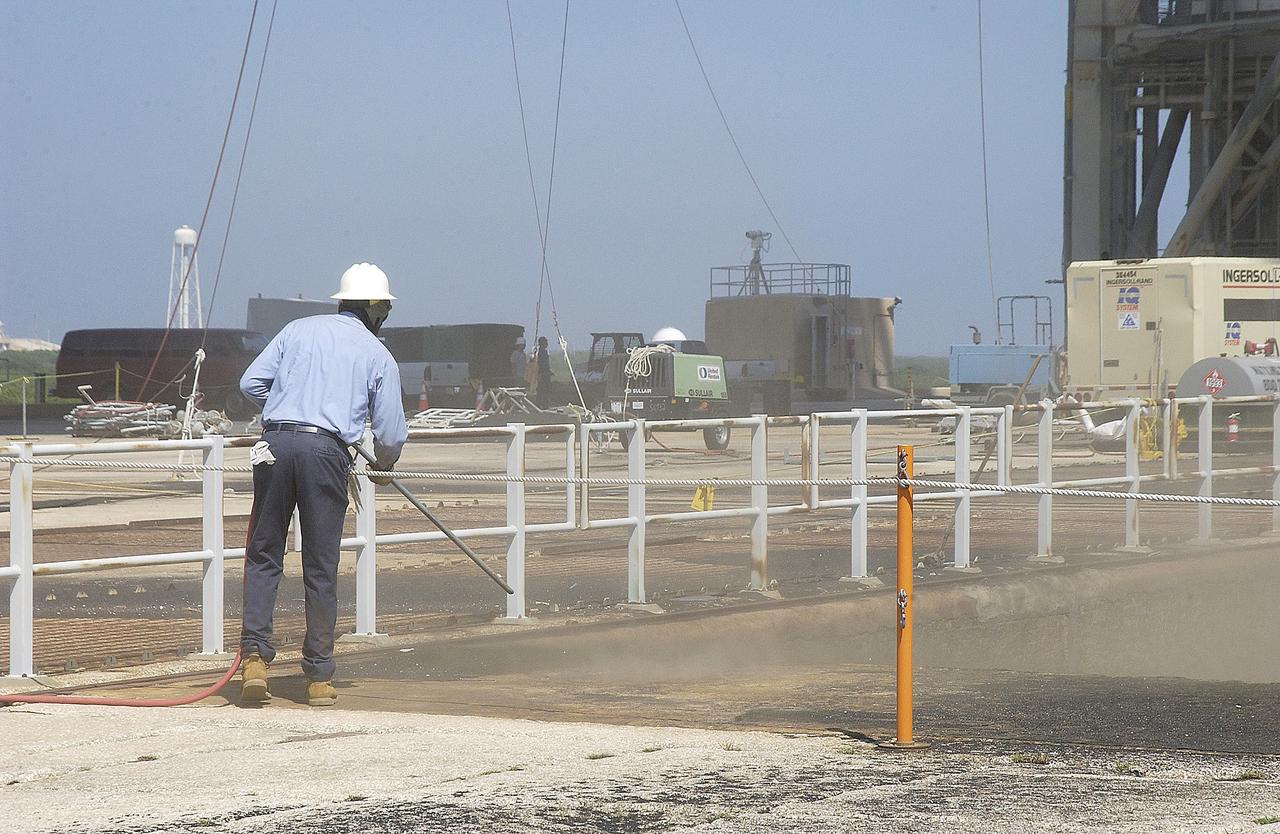 KENNEDY SPACE CENTER, FLA. - A worker sandblasts the surface behind the Mobile Launcher Platform on Launch Pad 39A .  Routine maintenance includes sandblasting and repainting as preventive means to minimize corrosion.
