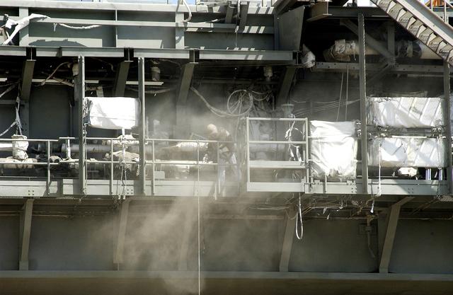 NASA image: KENNEDY SPACE CENTER, FLA. - Workers, covered in protective clothing and breathing apparatus, continue sandblasting on the Mobile Launcher Platform on Launch Pad 39A to remove corrosion before repainting.  Routine maintenance includes sandblasting and repainting as preventive means to minimize corrosion.