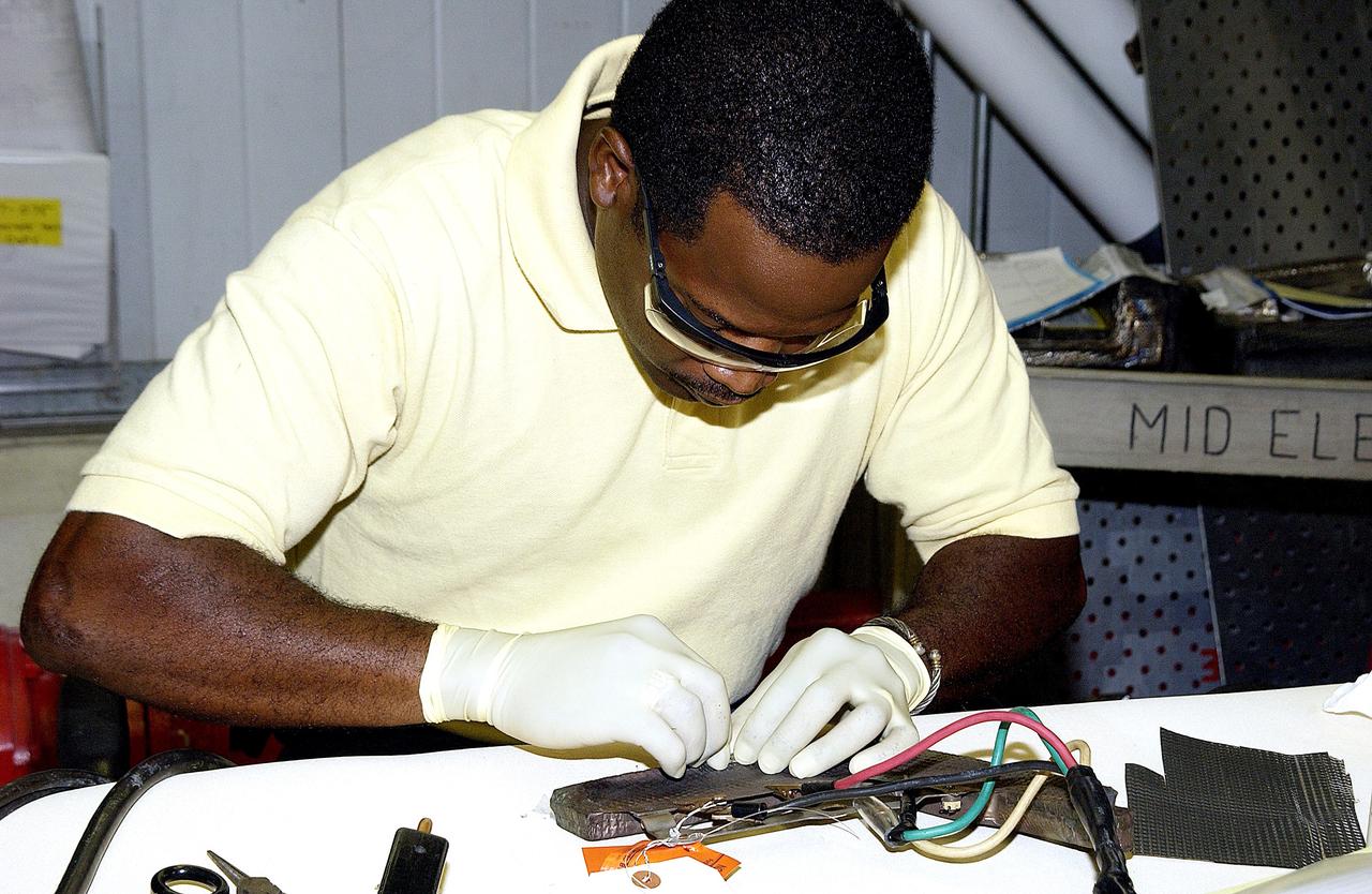 KENNEDY SPACE CENTER, FLA. -  United Space Alliance employee Anthony Simmons prepares to electroweld a crack formed in the insulator inside a Reinforced Carbon Carbon panel.   The gray carbon composite RCC panels are attached to the leading edge of the wing of the orbiters to withstand the aerodynamic forces experienced during launch and reentry, which can reach as high as 800 pounds per square foot.  The operating range of RCC is from minus 250º F to about 3,000º F, the temperature produced by friction with the atmosphere during reentry.