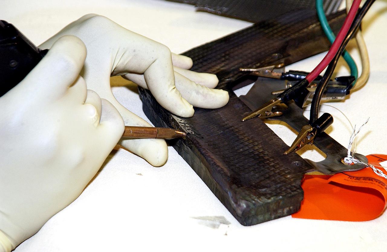 KENNEDY SPACE CENTER, FLA. -  United Space Alliance employee Anthony Simmons electrowelds a crack formed in the insulator inside a Reinforced Carbon Carbon panel.   The gray carbon composite RCC panels are attached to the leading edge of the wing of the orbiters to withstand the aerodynamic forces experienced during launch and reentry, which can reach as high as 800 pounds per square foot.  The operating range of RCC is from minus 250º F to about 3,000º F, the temperature produced by friction with the atmosphere during reentry.