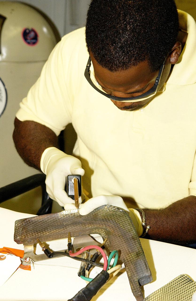 KENNEDY SPACE CENTER, FLA. -   United Space Alliance employee Anthony Simmons continues electrowelding on an insulator inside a Reinforced Carbon Carbon panel.   The gray carbon composite RCC panels are attached to the leading edge of the wing of the orbiters to withstand the aerodynamic forces experienced during launch and reentry, which can reach as high as 800 pounds per square foot.  The operating range of RCC is from minus 250º F to about 3,000º F, the temperature produced by friction with the atmosphere during reentry.