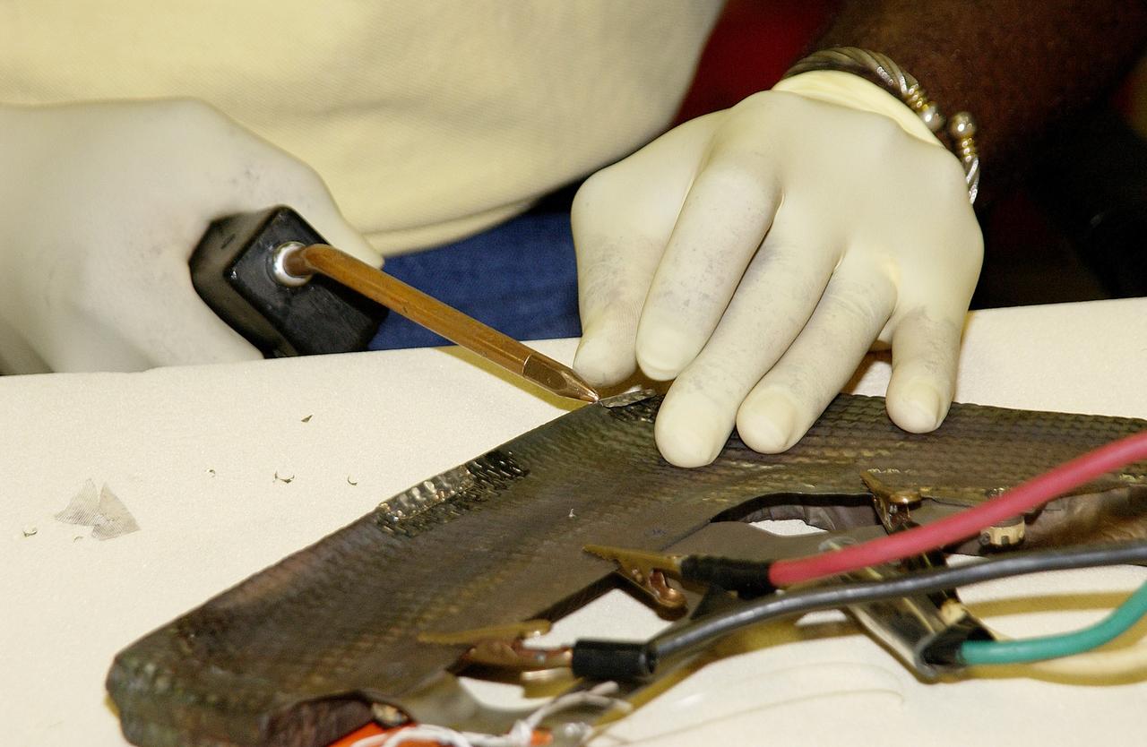 KENNEDY SPACE CENTER, FLA. -   United Space Alliance employee Anthony Simmons continues electrowelding on an insulator inside a Reinforced Carbon Carbon panel.   The gray carbon composite RCC panels are attached to the leading edge of the wing of the orbiters to withstand the aerodynamic forces experienced during launch and reentry, which can reach as high as 800 pounds per square foot.  The operating range of RCC is from minus 250º F to about 3,000º F, the temperature produced by friction with the atmosphere during reentry.