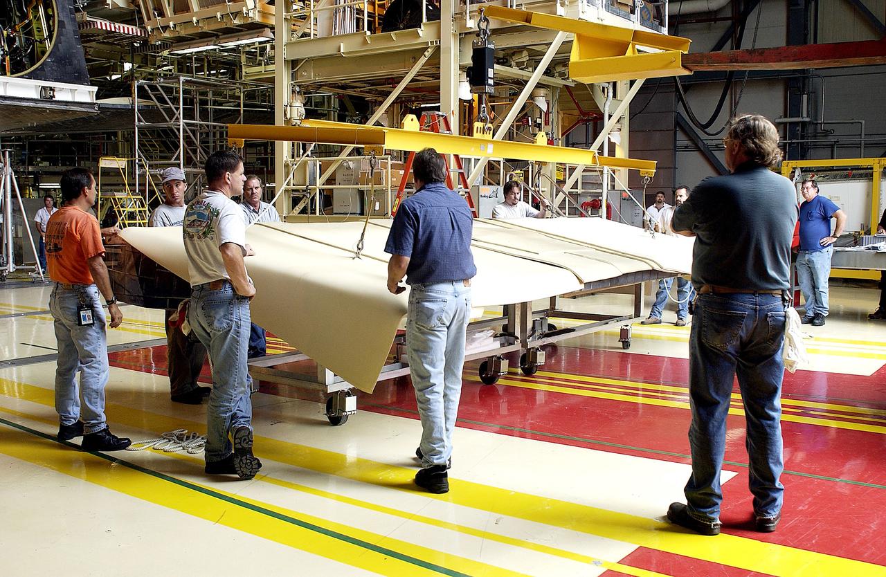 KENNEDY SPACE CENTER, FLA. -   Workers in the Orbiter Processing Facility get ready to lift and install the rear body flap on orbiter Discovery.  The body flap, which is temporarily under protective covering, attaches below the main engines.