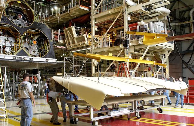 NASA image: KENNEDY SPACE CENTER, FLA. -   Workers in the Orbiter Processing Facility get ready to lift and install the rear body flap on orbiter Discovery.  The body flap, which is temporarily under protective covering, attaches below the main engines.