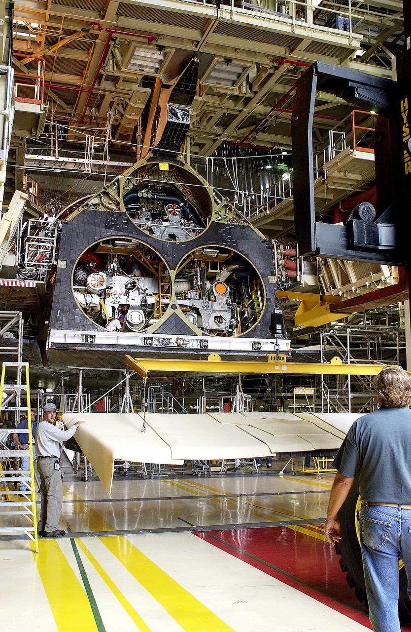 KENNEDY SPACE CENTER, FLA. -  Workers in the Orbiter Processing Facility get ready to lift and install the rear body flap on orbiter Discovery.  The body flap, which is temporarily under protective covering, attaches below the main engines.