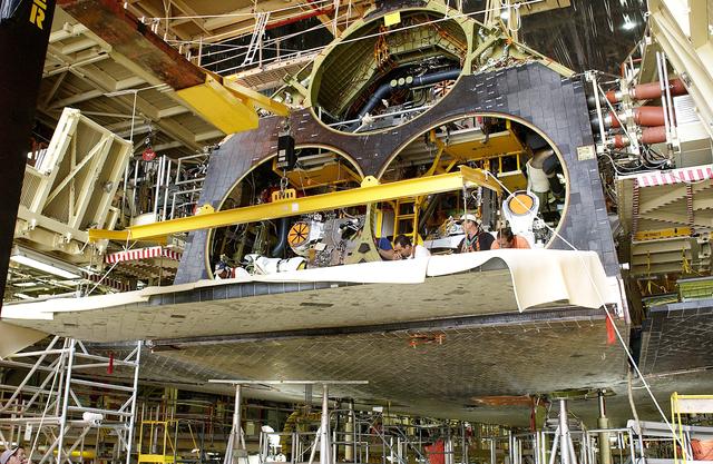 NASA image: KENNEDY SPACE CENTER, FLA. - In the Orbiter Processing Facility, the rear body flap is lifted into place on the orbiter Discovery.  The body flap, which is temporarily under protective covering,  attaches below the main engines.