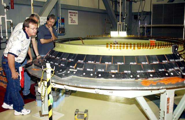 NASA image: KENNEDY SPACE CENTER, FLA. -  United Space Alliance employees (from left) Daryl Burke, Jay Beason and Tom Summers check new tiles installed on the heat shield of main engine 1 for the orbiter Discovery.  A heat shield is a protective layer on a spacecraft designed to protect it from the high temperatures, usually those that result from aerobraking during reentry into the Earth’s atmosphere.