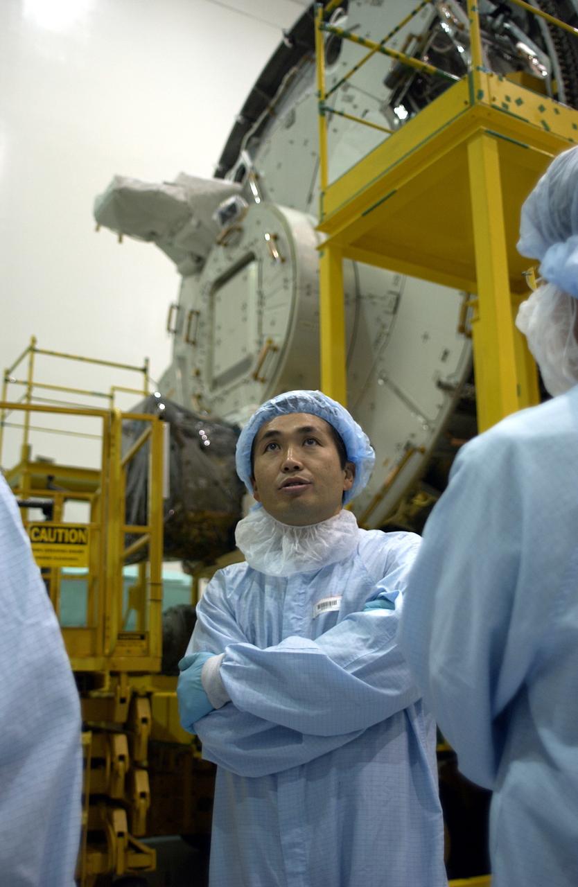 KENNEDY SPACE CENTER, FLA. -  In the Space Station Processing Facility, Japanese astronaut Koichi Wakata is dressed in protective clothing before entering the Pressurized Module, or PM, behind him.  Part of the Japanese Experiment Module (JEM), the PM provides a shirt-sleeve environment in which astronauts on the International Space Station can conduct microgravity experiments. There are a total of 23 racks, including 10 experiment racks, inside the PM providing a power supply, communications, air conditioning, hardware cooling, water control and experiment support functions.
