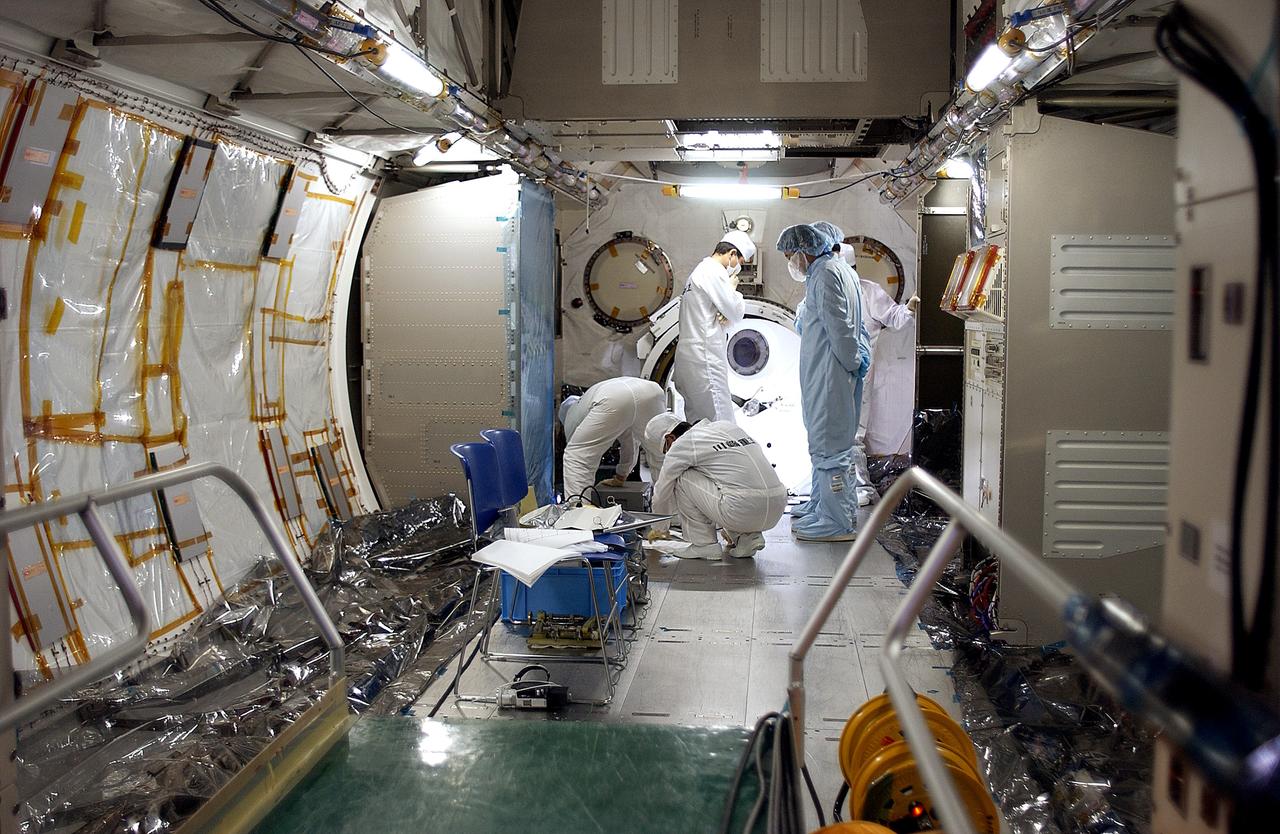 KENNEDY SPACE CENTER, FLA. - In the Space Station Processing Facility, Japanese astronaut Koichi Wakata,  dressed in blue protective clothing (at right),  looks at the inside of the Pressurized Module, or PM, part of the Japanese Experiment Module (JEM), along with technicians.  The PM provides a shirt-sleeve environment in which astronauts on the International Space Station can conduct microgravity experiments. There are a total of 23 racks, including 10 experiment racks, inside the PM providing a power supply, communications, air conditioning, hardware cooling, water control and experiment support functions.