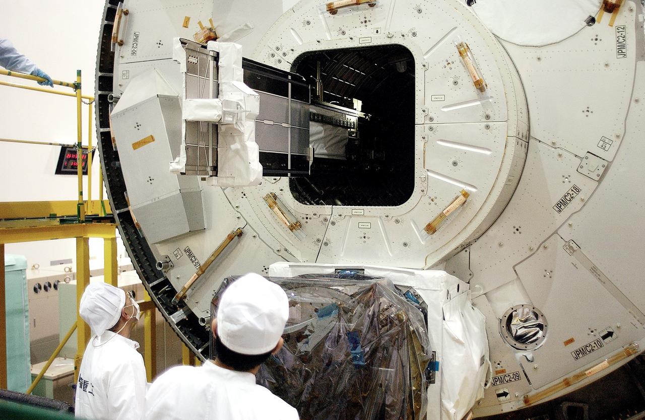 KENNEDY SPACE CENTER, FLA. - In the Space Station Processing Facility, technicians on the floor watch as a tray is extended from inside the Pressurized Module, or PM, part of the Japanese Experiment Module (JEM).   The PM provides a shirt-sleeve environment in which astronauts on the International Space Station can conduct microgravity experiments. There are a total of 23 racks, including 10 experiment racks, inside the PM providing a power supply, communications, air conditioning, hardware cooling, water control and experiment support functions.