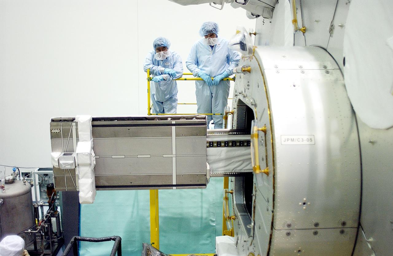 KENNEDY SPACE CENTER, FLA. -  In the Space Station Processing Facility, Japanese astronaut Koichi Wakata (top left) and technicians watch as a tray is extended from inside the Pressurized Module, or PM, part of the Japanese Experiment Module (JEM).   The PM provides a shirt-sleeve environment in which astronauts on the International Space Station can conduct microgravity experiments. There are a total of 23 racks, including 10 experiment racks, inside the PM providing a power supply, communications, air conditioning, hardware cooling, water control and experiment support functions.