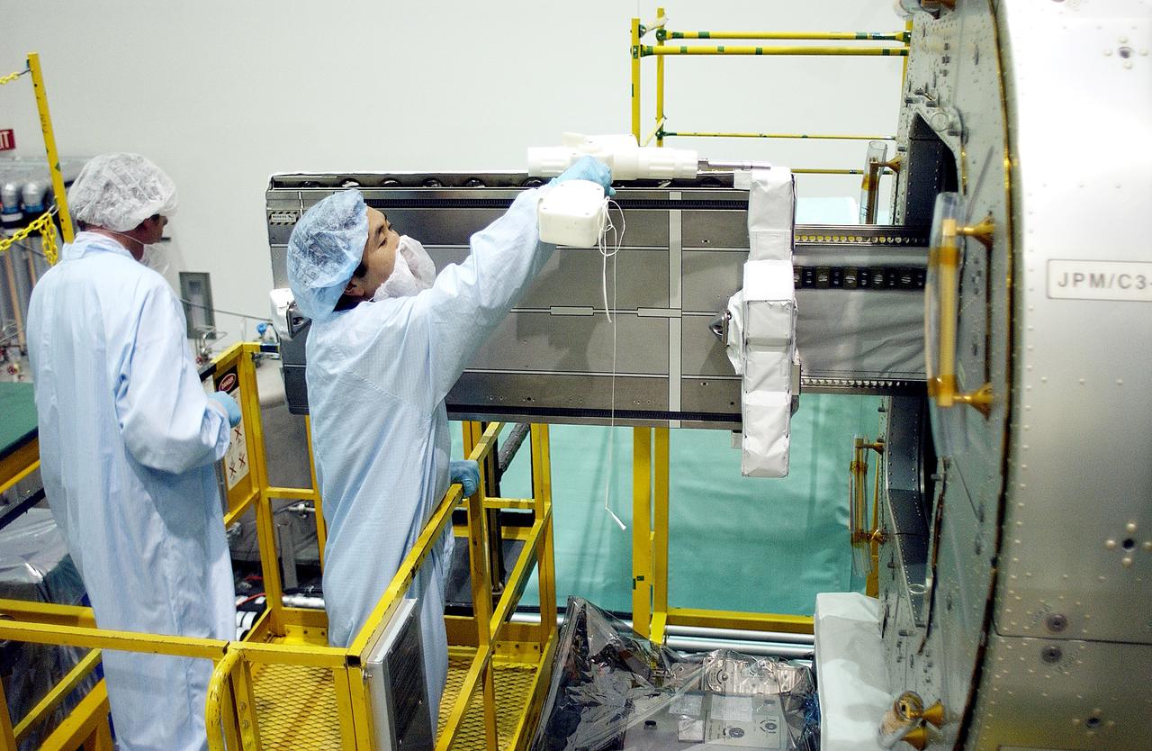 KENNEDY SPACE CENTER, FLA. -   Japanese astronaut Koichi Wakata (right) works with a tray extended  from inside the Pressurized Module, or PM, part of the Japanese Experiment Module (JEM).   The PM provides a shirt-sleeve environment in which astronauts on the International Space Station can conduct microgravity experiments. There are a total of 23 racks, including 10 experiment racks, inside the PM providing a power supply, communications, air conditioning, hardware cooling, water control and experiment support functions.