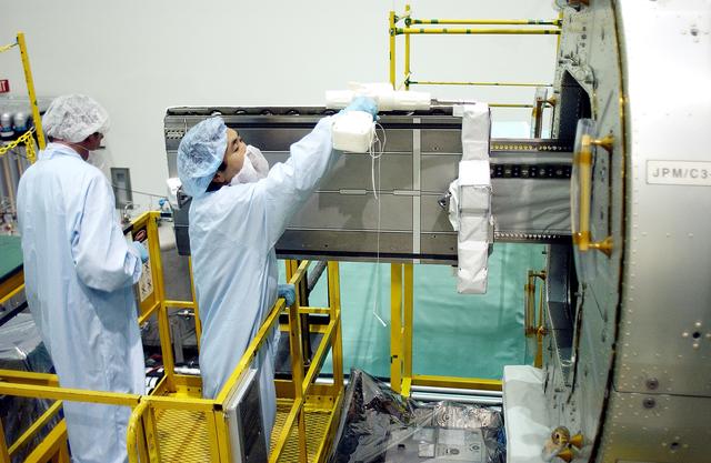 NASA image: KENNEDY SPACE CENTER, FLA. -   Japanese astronaut Koichi Wakata (right) works with a tray extended  from inside the Pressurized Module, or PM, part of the Japanese Experiment Module (JEM).   The PM provides a shirt-sleeve environment in which astronauts on the International Space Station can conduct microgravity experiments. There are a total of 23 racks, including 10 experiment racks, inside the PM providing a power supply, communications, air conditioning, hardware cooling, water control and experiment support functions.
