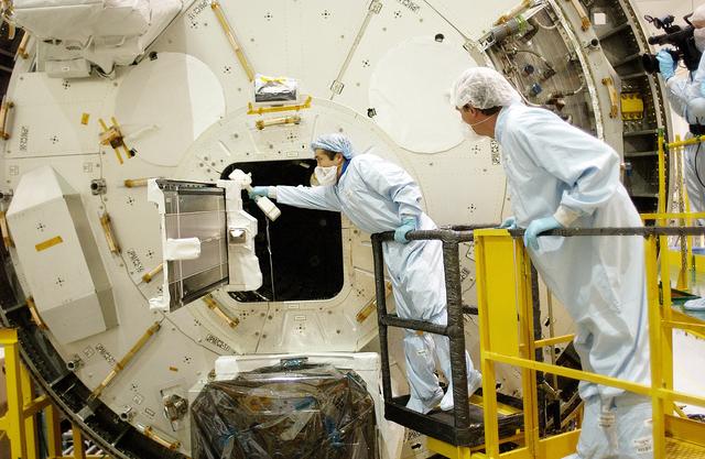 NASA image: KENNEDY SPACE CENTER, FLA. -  Japanese astronaut Koichi Wakata (left) works with a tray extended from inside the Pressurized Module, or PM, part of the Japanese Experiment Module (JEM).   The PM provides a shirt-sleeve environment in which astronauts on the International Space Station can conduct microgravity experiments. There are a total of 23 racks, including 10 experiment racks, inside the PM providing a power supply, communications, air conditioning, hardware cooling, water control and experiment support functions.