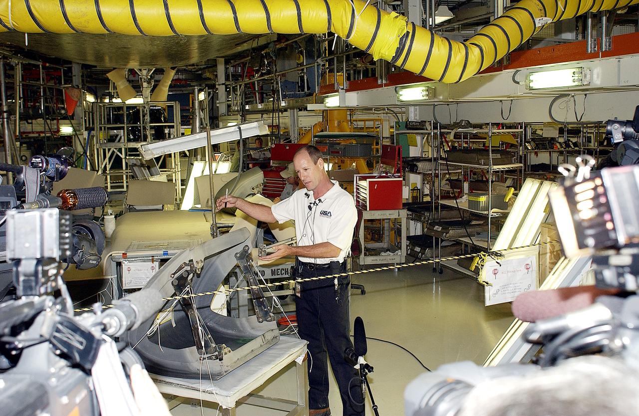 KENNEDY SPACE CENTER, FLA. -  In the Orbiter Processing Facility (OPF), Rick Beckwith, an orbiter engineer with United Space Alliance, explains to the media the reinstallation of the Reinforced Carbon-Carbon panels on Atlantis’ wing leading edge.  The media was invited to tour the OPF at KSC and to see the orbiter Atlantis as it is being prepared for Return to Flight.  Both local and national reporters representing print and TV networks were able to see work in progress on Atlantis, also including wiring inspections and checks of the engines in the Orbital Maneuvering System.