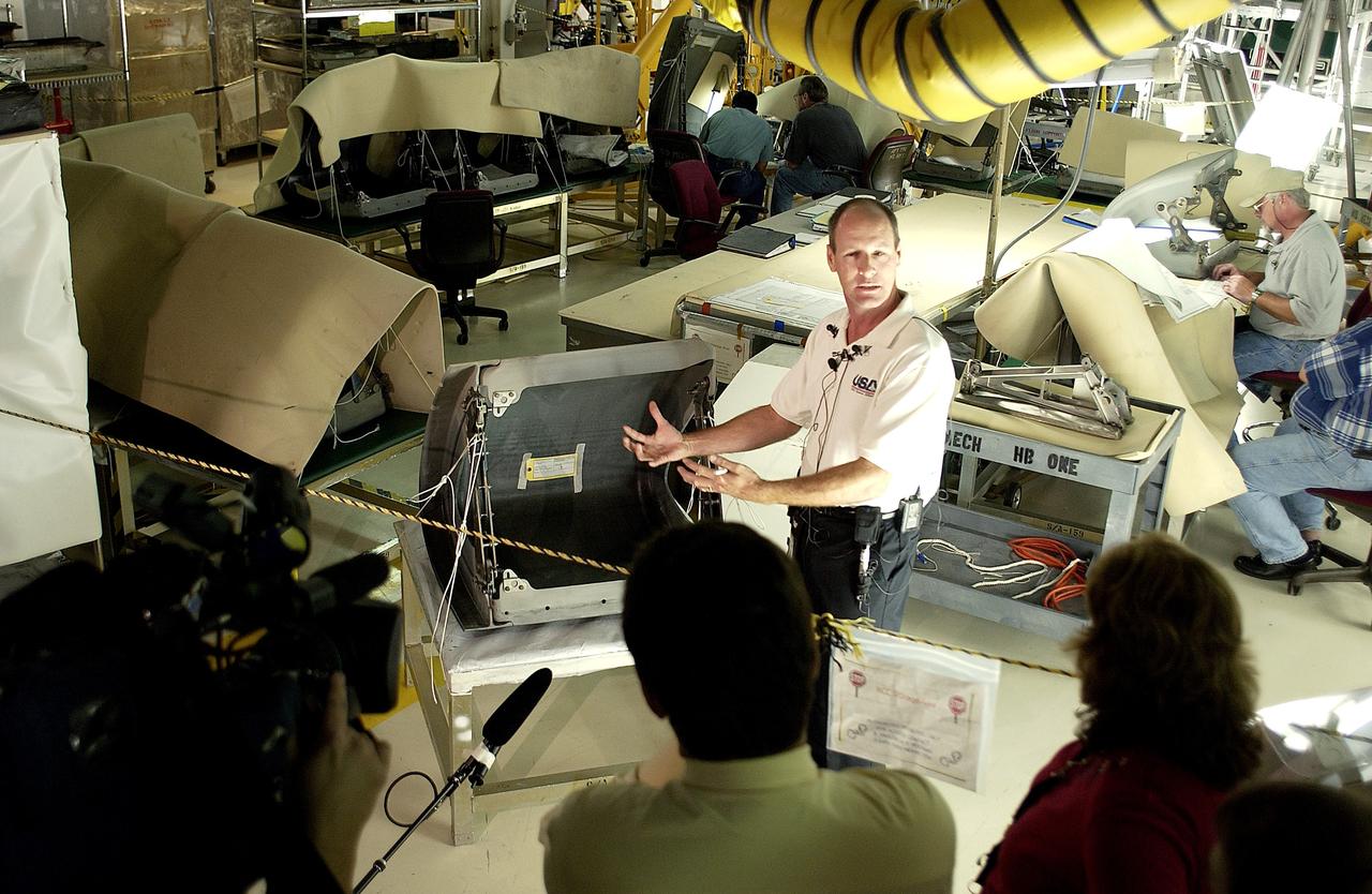 KENNEDY SPACE CENTER, FLA. -  In the Orbiter Processing Facility (OPF), Rick Beckwith, an orbiter engineer with United Space Alliance, explains to the media the reinstallation of the Reinforced Carbon-Carbon panels on the orbiter Atlantis’ wing leading edge.  The media was invited to tour the OPF at KSC and to see the orbiter Atlantis as it is being prepared for Return to Flight.  Both local and national reporters representing print and TV networks were able to see work in progress on Atlantis, also including wiring inspections and checks of the engines in the Orbital Maneuvering System.