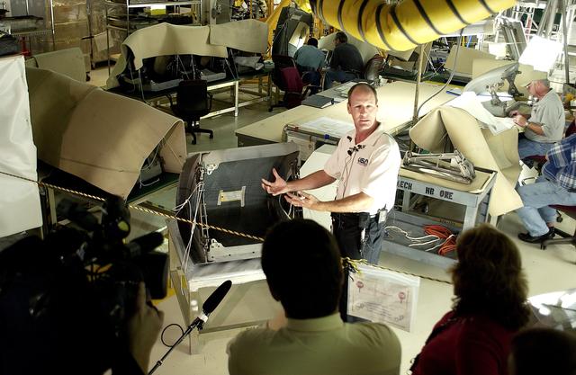 NASA image: KENNEDY SPACE CENTER, FLA. -  In the Orbiter Processing Facility (OPF), Rick Beckwith, an orbiter engineer with United Space Alliance, explains to the media the reinstallation of the Reinforced Carbon-Carbon panels on the orbiter Atlantis’ wing leading edge.  The media was invited to tour the OPF at KSC and to see the orbiter Atlantis as it is being prepared for Return to Flight.  Both local and national reporters representing print and TV networks were able to see work in progress on Atlantis, also including wiring inspections and checks of the engines in the Orbital Maneuvering System.
