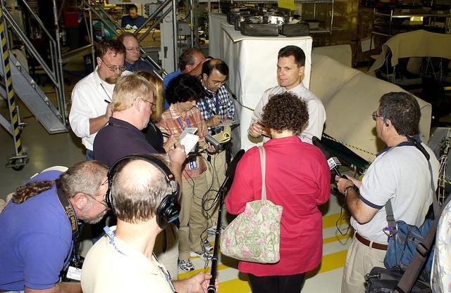 NASA image: KENNEDY SPACE CENTER, FLA. -  NASA Vehicle Manager Scott Thurston (facing camera) talks to the media in the Orbiter Processing Facility.  The media was invited to see the orbiter Atlantis as it is being prepared for Return to Flight.  Both local and national reporters representing print and TV networks were able to see work in progress on Atlantis, including the reinstallation of the Reinforced Carbon-Carbon panels on the orbiter’s wing leading edge; wiring inspections; and checks of the engines in the Orbital Maneuvering System.