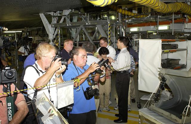 NASA image: KENNEDY SPACE CENTER, FLA. -  In the Orbiter Processing Facility, while a few photographers (left) set up for photos of a Reinforced Carbon-Carbon panel at far right, NASA Vehicle Manager Scott Thurston (right) talks to other media.   The media was invited to see the orbiter Atlantis as it is being prepared for Return to Flight.  Both local and national reporters representing print and TV networks were able to see work in progress on Atlantis, including the reinstallation of the Reinforced Carbon-Carbon panels on the orbiter’s wing leading edge; wiring inspections; and checks of the engines in the Orbital Maneuvering System.