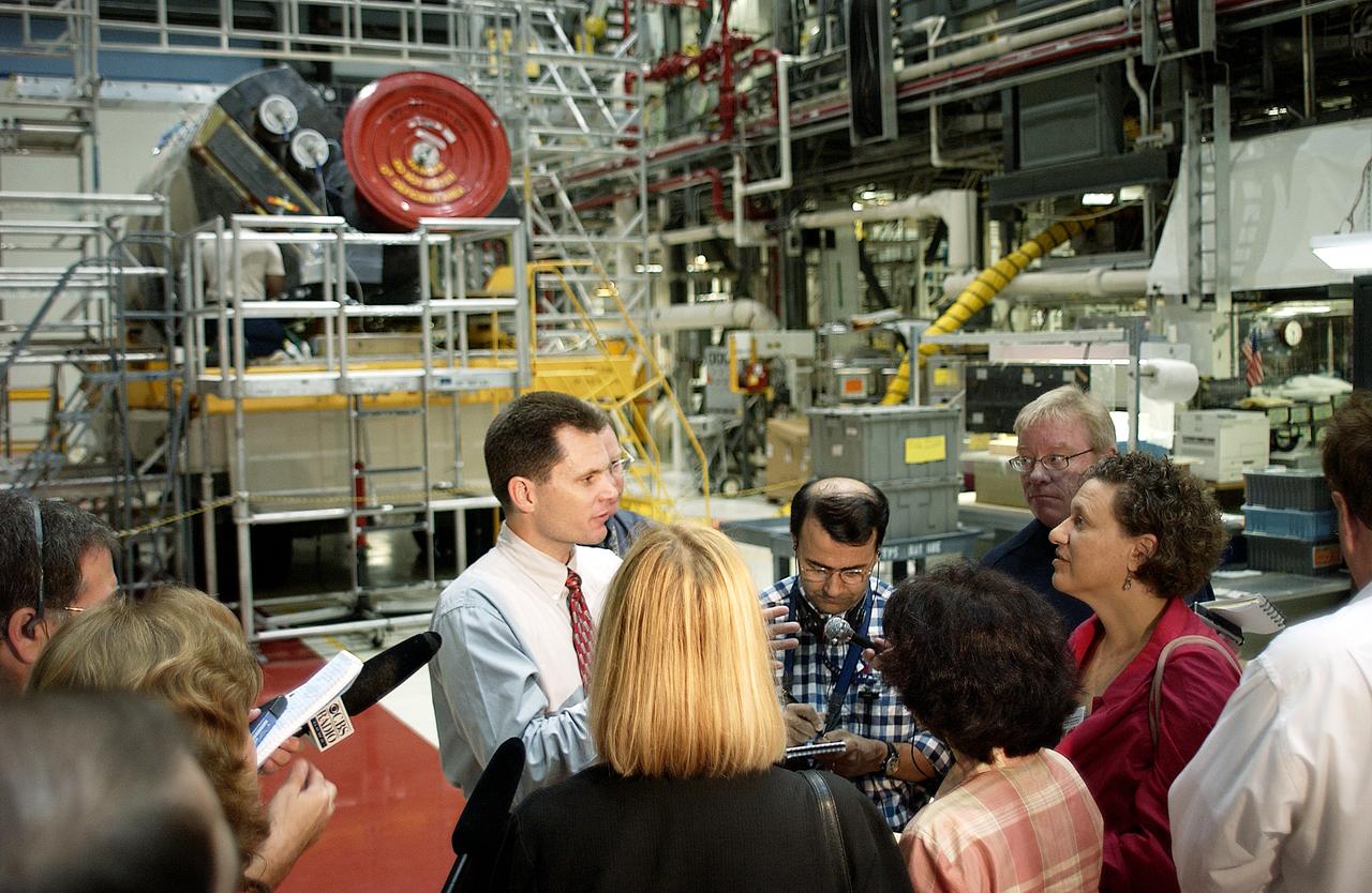 The media gather around NASA Vehicle Manager Scott Thurston (white shirt, center) who talks about some of the work being done on the orbiter Atlantis as it is being prepared for Return to Flight in the Orbiter Processing Facility. Both local and national reporters representing print and TV networks were able to see work in progress on Atlantis, including the reinstallation of the Reinforced Carbon-Carbon panels on the orbiter’s wing leading edge; wiring inspections; and checks of the engines in the Orbital Maneuvering System.