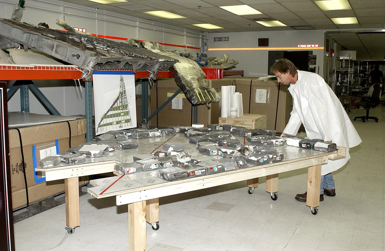 In the Vehicle Assembly Building, Richard Risley, with United Space Alliance, moves a table holding pieces of tile from Columbia’s wing. All of the pieces received and collected in the Columbia Reconstruction Hangar have been catalogued and moved to a permanent site in the VAB.