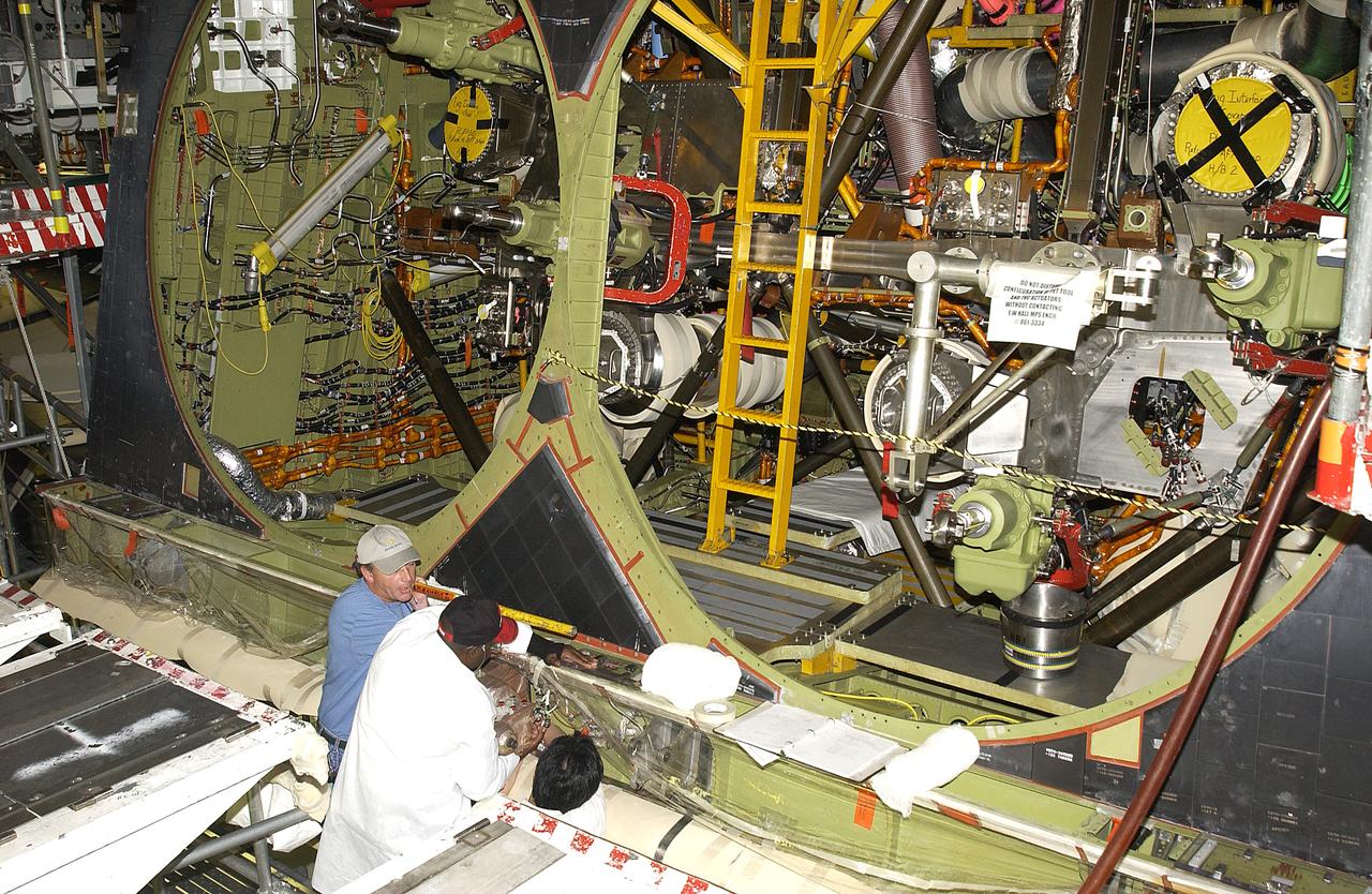 In the Orbiter Processing Facility, Tim Chastain (left) and John Peterson (right), with United Space Alliance, prepare to remove the body flap actuator from the orbiter Endeavour. The work is part of return to flight activities on the orbiter fleet.