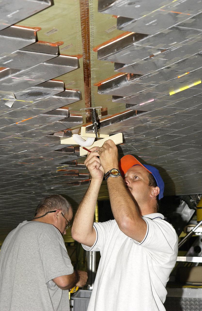 In the Orbiter Processing Facility, David Sanborn and Rick Cady, with United Space Alliance, check tiles on the underside of Endeavour. Tile check is part of routine maintenance and return to flight activities on the orbiter fleet. 